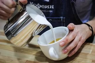 В широкую чашку наливают молоко из железного кувшина
