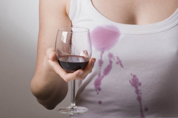 Девушка в белой майке держит бокал с красным вином