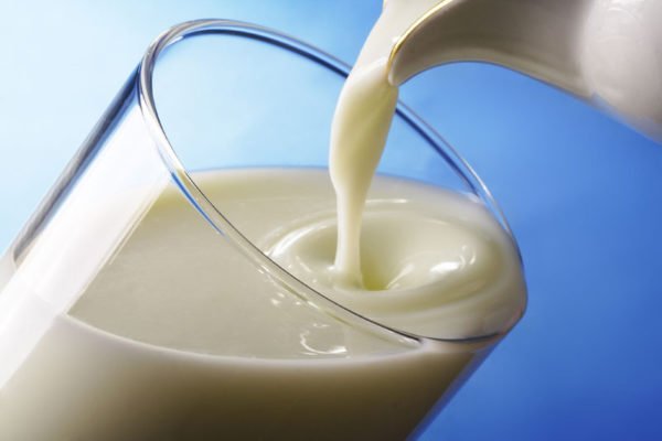 Молоко наливают из кувшина в стакан