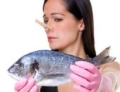Девушка с прищепкой на носу держит рыбу