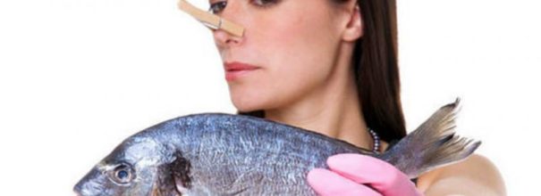 Девушка с прищепкой на носу держит рыбу