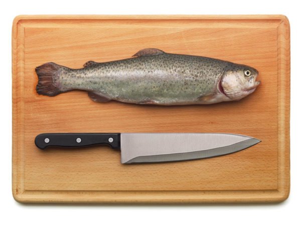 Рыба на деревянной разделочной доске и нож