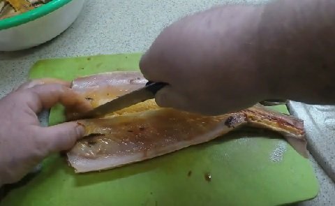 Ножом режут тушку стерляди на две части
