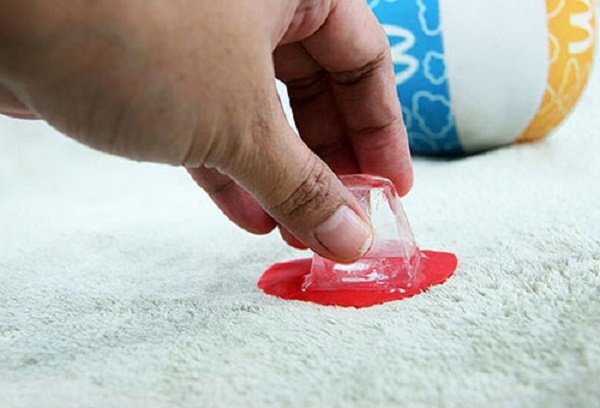 Красный пластилин на ковре замораживают кубиком льда