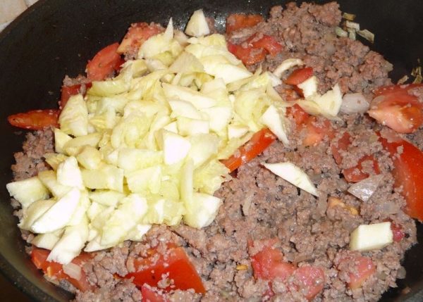 Фарш, измельчённая мякоть кабачков и нарезанные кубиками помидоры в сковороде