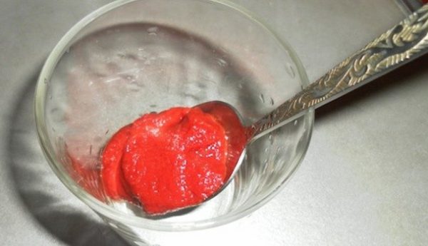 Ложка с томатной пастой в стеклянном стакане