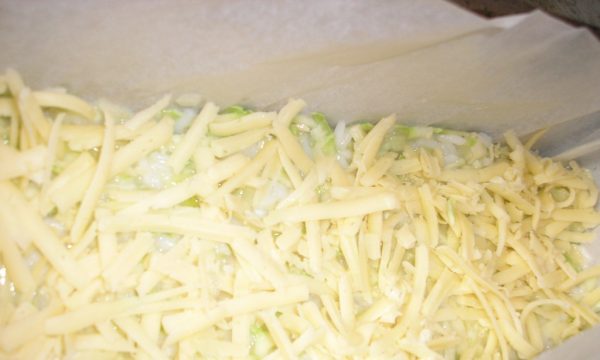 Заготовка для запеканки из кабачков, посыпанная тёртым сыром