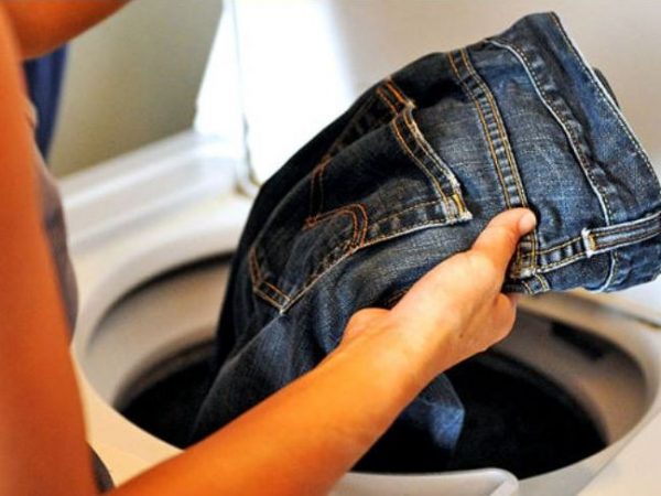 женщина достаёт джинсы из стиральной машины