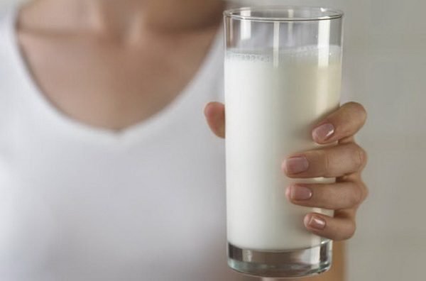 Девушка в белом держит стакан молока