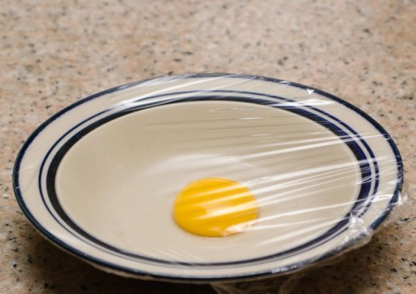 Яичный желток в тарелке под пищевой плёнкой