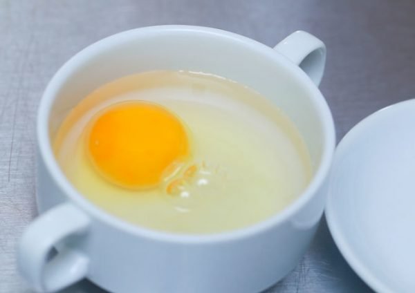 Сырое яйцо без скорлупы в кружке с водой