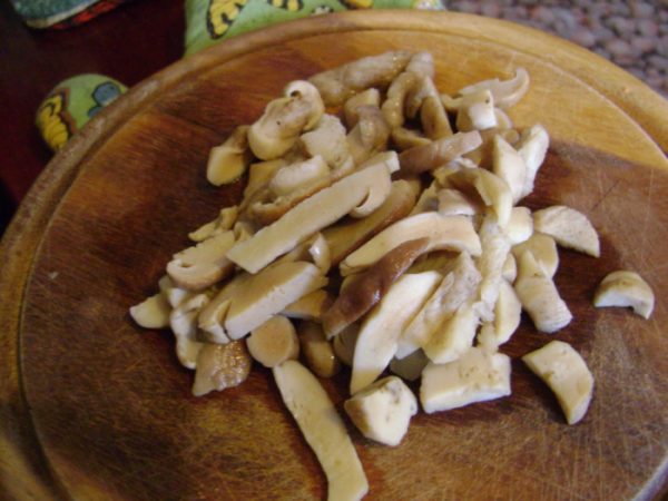 Кусочки отварных грибов на деревянной доске