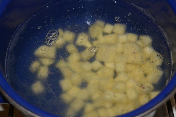 Кубики сырого картофеля в кастрюле с водой