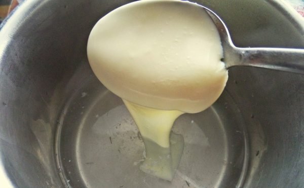 Ложка с плавленым сыром над кастрюлей с водой