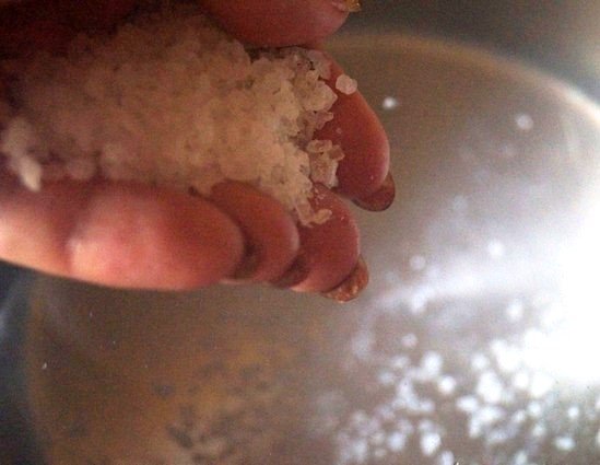 Вода в кастрюле и соль в руке