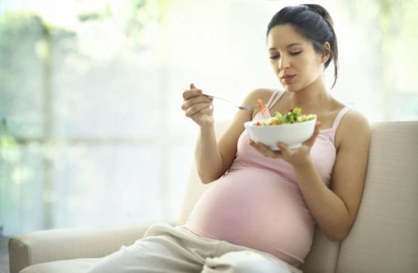 беременная сидя ест салат