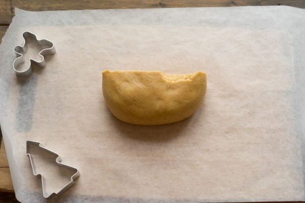 Кусочек теста и металлические формы для печенья на листе пекарской бумаги
