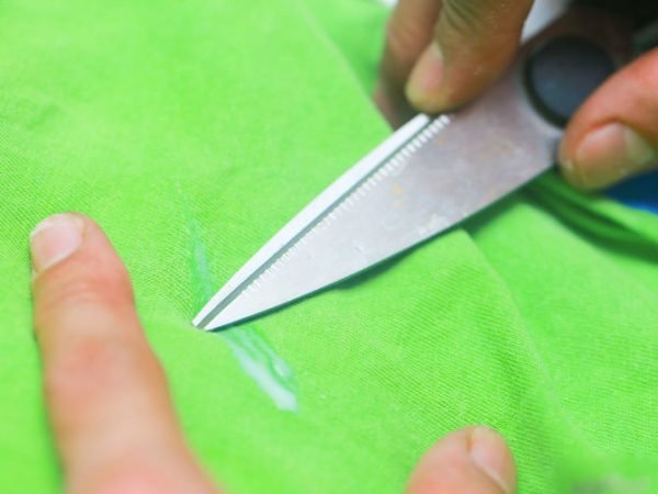 Ножницами убирают след от ПВА с зелёной ткани