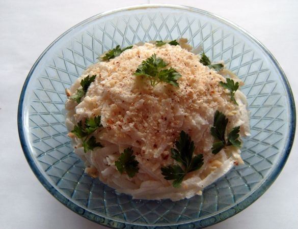 Салат с дайконом и сыром в салатнике, украшенный свежей петрушкой