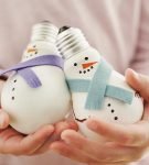 Два снеговика из лампочек в руках