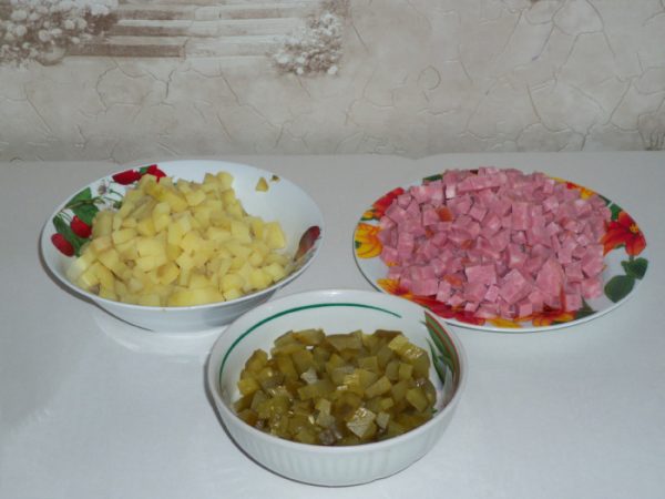 Нарезанные кубиками солёные огурцы, ветчина и отварной картофель в отдельных тарелках