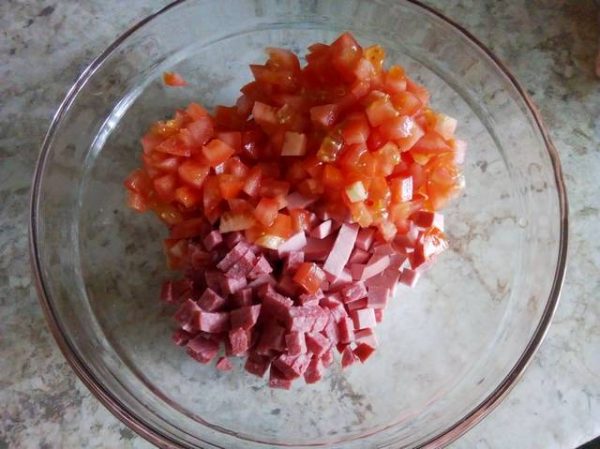 Нарезанные кубиками свежие помидоры и колбасные изделия