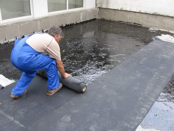 Процесс укладки рубероида на бетонную крышу