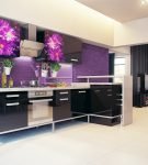 Большая кухня с чёрно-фиолетовым гарнитуром и яркой стеной