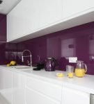 Сочетание фиолетового фартука и белой мебели на небольшой кухне