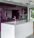 Белый стол-остров и фиолетовый гарнитур на кухне в доме