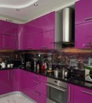 Тёмный фартук, дополняющий фиолетовый гарнитур на кухне с белым потолком
