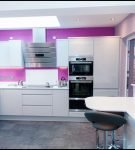 Белая мебель на фоне фиолетовой стены кухни