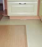 Коричневый ламинат и фисташковая плитка на полу кухни