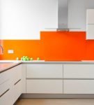 Сочетание белой мебели и оранжевого фартука в дизайне кухни