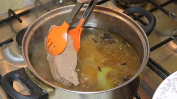 Извлечение мяса из бульона с помощью кулинарных щипцов