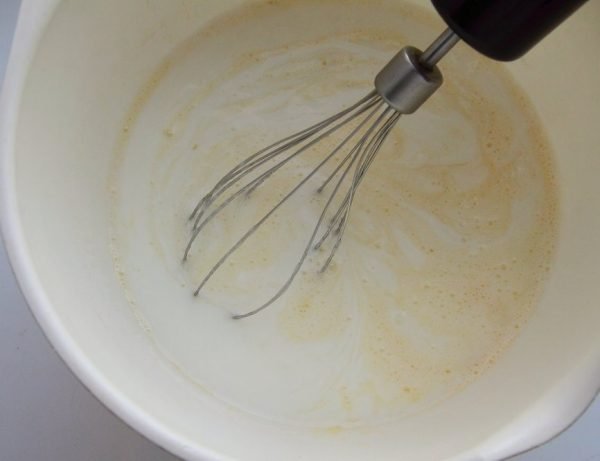Смешивание яичной смеси с кефиром в большой миске с помощью венчика