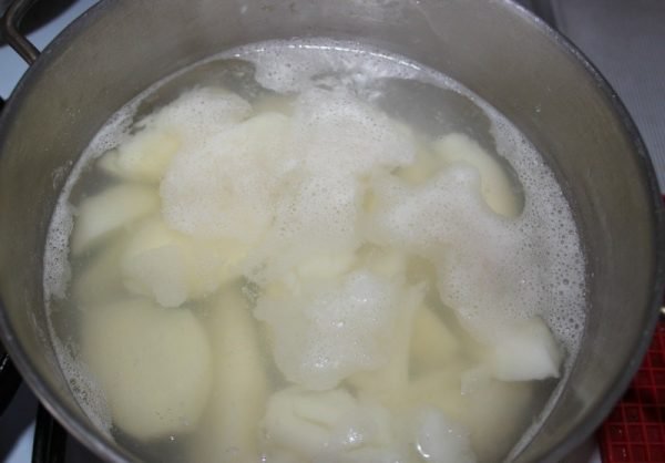 Кусочки сырого картофеля в кастрюле с закипающей водой