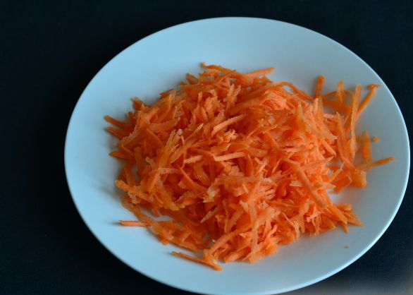 Натёртая на тёрке морковь на тарелке