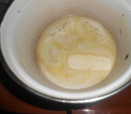 Растопленное сливочное масло в большой кастрюле на плите