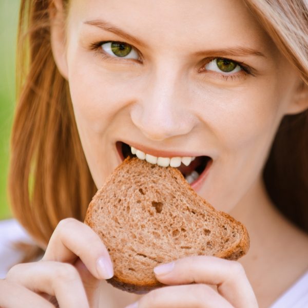Девушка ест свежий хлеб