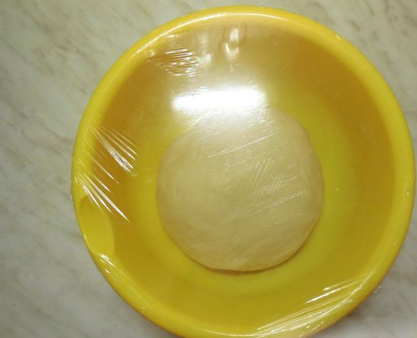 Шар теста в жёлтой миске под пищевой плёнкой