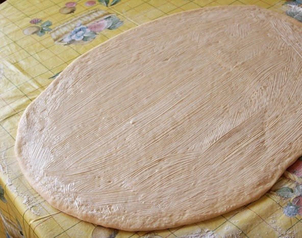 Смазанное размягчённым сливочным маслом сырое тесто на столе