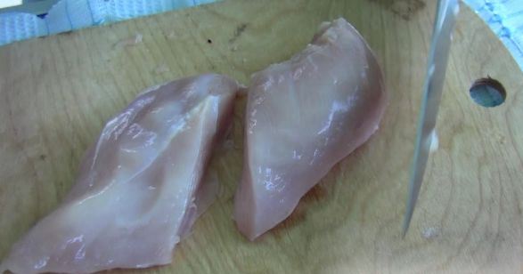 Сырое куриное филе на разделочной доске и нож