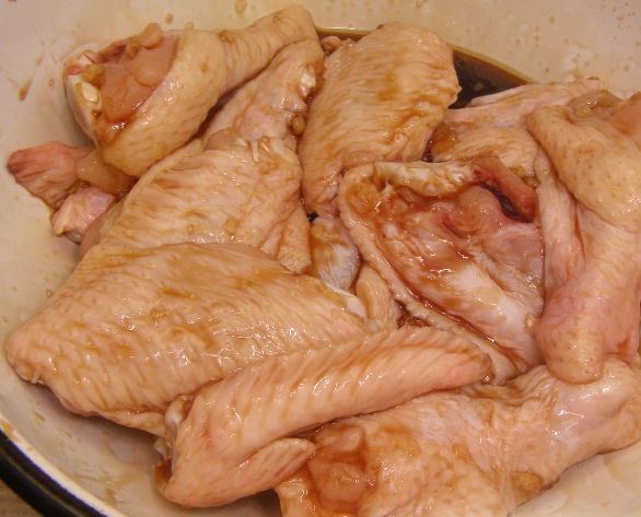 Сырые куриные крылышки в миске с маринадом
