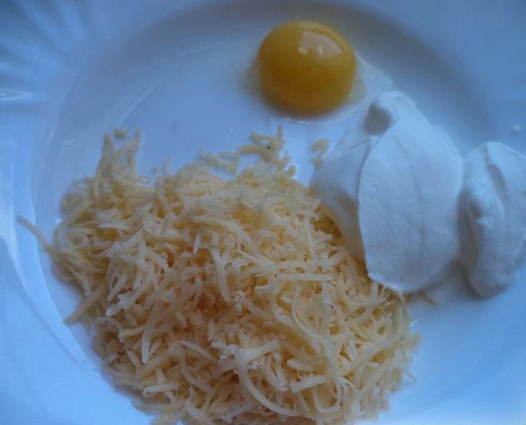 Тёртый твёрдый сыр, яичный желток и сметана на тарелке