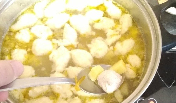 Суп с фрикадельками и клёцками в большой кастрюле на плите