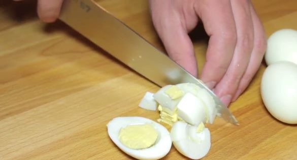 Нарезка варёных яиц на деревянной разделочной доске