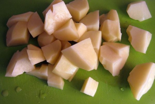 Кусочки сырого картофеля на разделочной доске