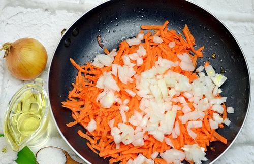 Натёртая на крупной тёрке морковь с репчатым луком в сковороде