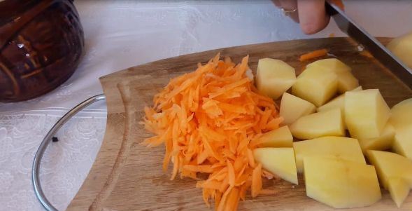 Нарезанный кубиками сырой картофель и тёртая морковь на разделочной доске